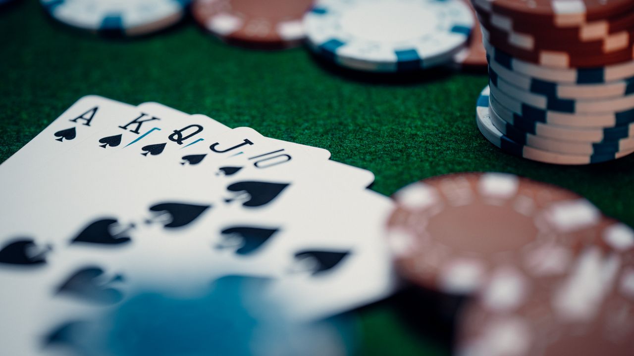 Close-up of a royal flush poker hand surrounded by colorful chips on a green table.